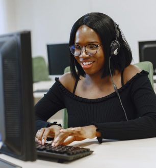 African woman sitting in computer science class. Lady with glasses. Female student sitting at the computer.